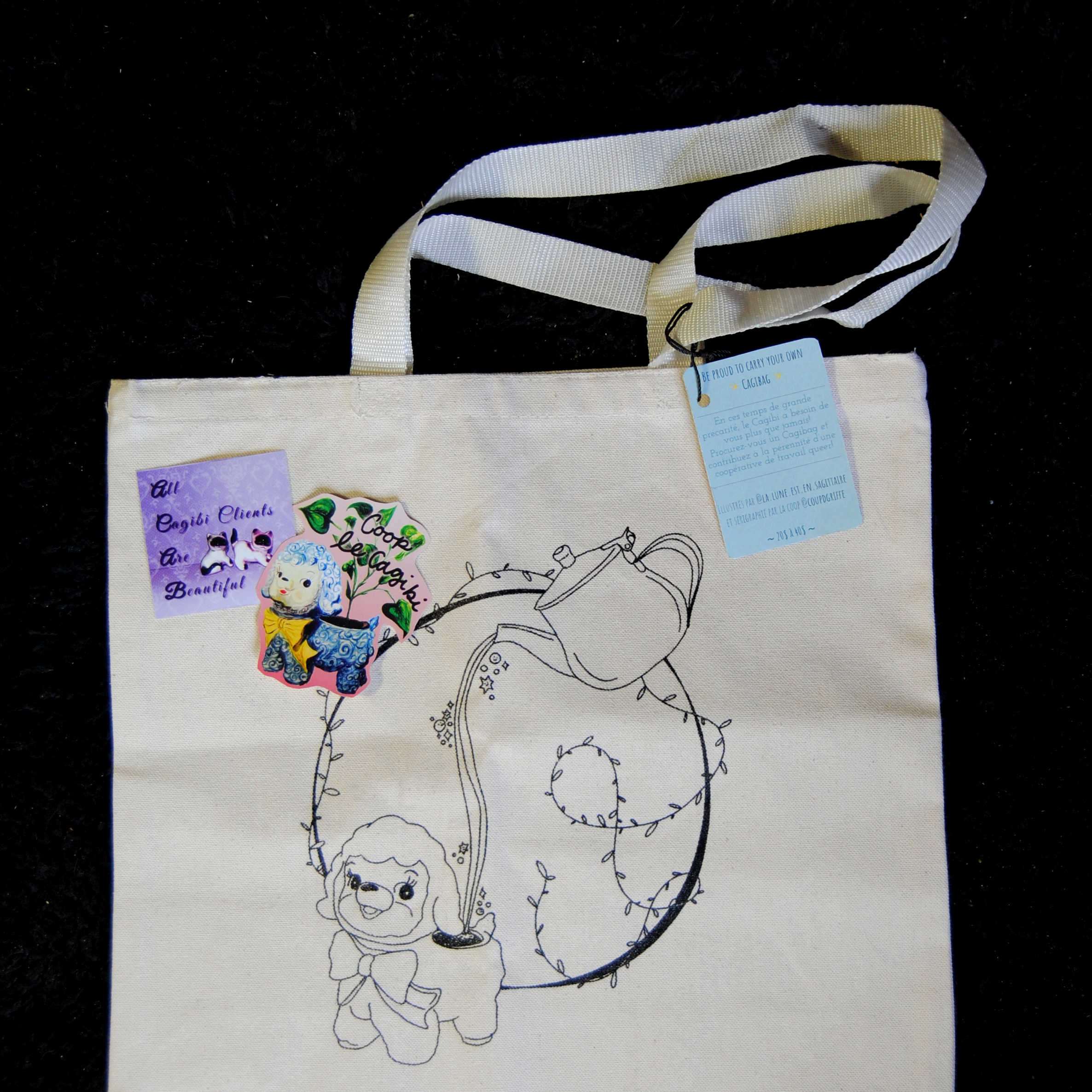 un tote bag avec une image à l'effigie d'un bibelot, ainsi que des autocollants